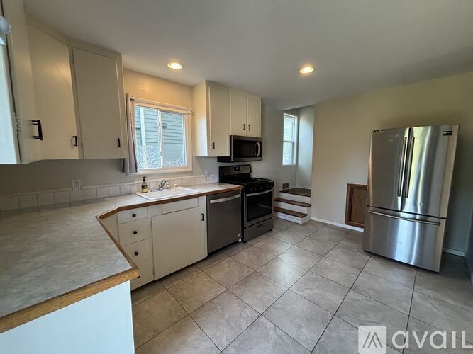 A kitchen with a refrigerator, sink, and cabinets.