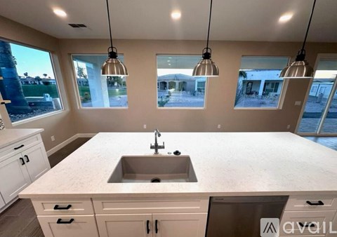 A kitchen with a large island and pendant lights.