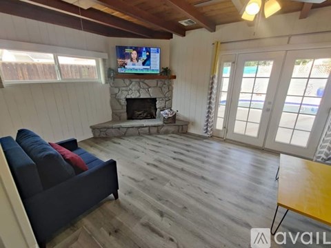 A living room with a fireplace and a television on the wall.