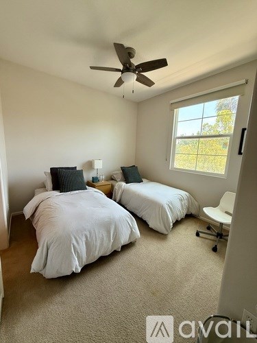 A bedroom with two beds and a ceiling fan.