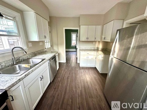 A kitchen with white cabinets and a stainless steel refrigerator.