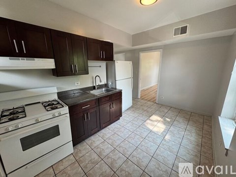 A kitchen with white appliances and dark brown cabinets.