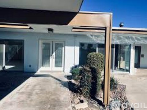A modern house with a glass door and a small garden in front.