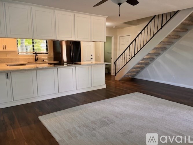 A kitchen with white cabinets and a staircase.