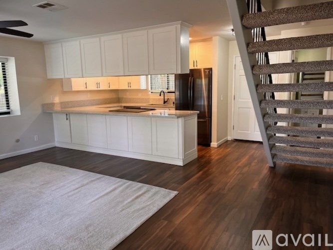 A kitchen with white cabinets and a staircase.