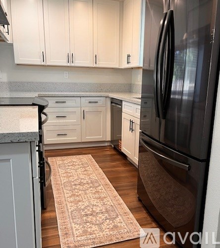 A kitchen with a rug on the floor and a refrigerator on the right.