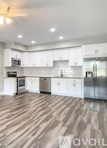 A kitchen with white cabinets and wooden flooring.