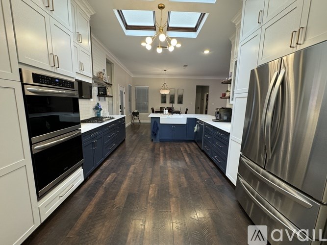 A modern kitchen with dark wood floors and stainless steel appliances.