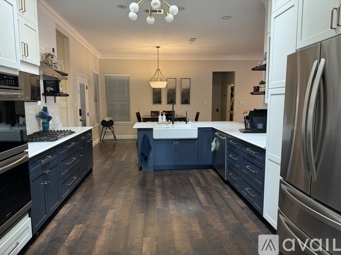 A modern kitchen with dark wood floors and stainless steel appliances.