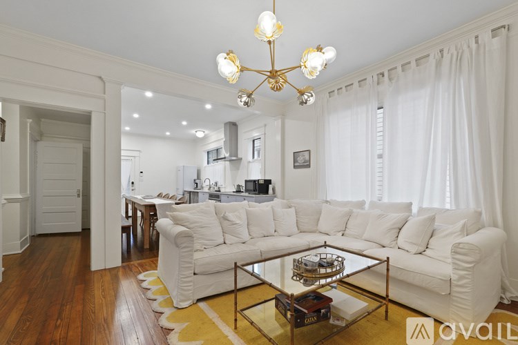 A living room with a white sofa and a chandelier.