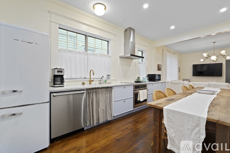 A kitchen with white appliances and wooden floors.