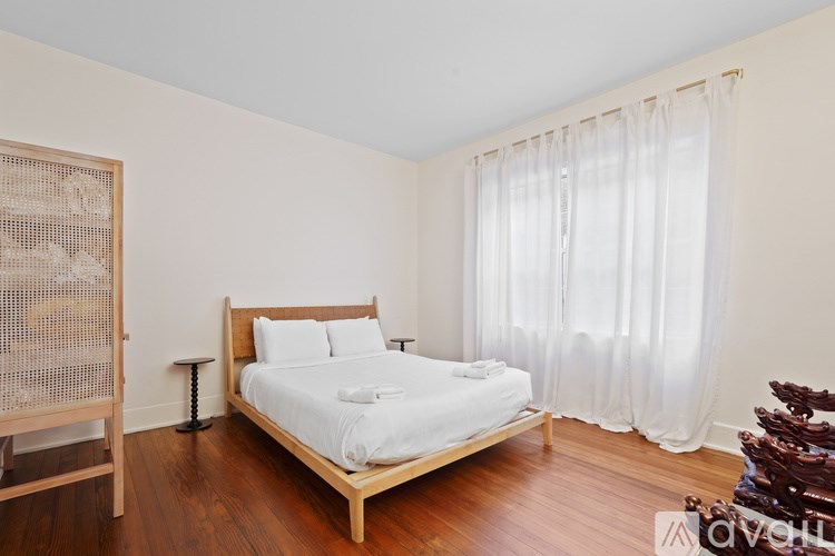 A bedroom with a bed, wooden furniture, and a window with curtains.