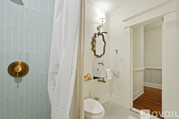 A bathroom with a toilet, a shower curtain, and a mirror.