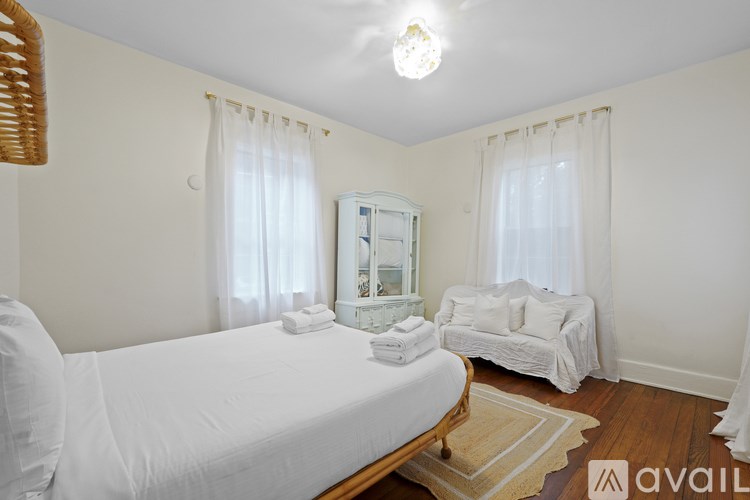 A bedroom with a large bed and a couch with a mirror above it.