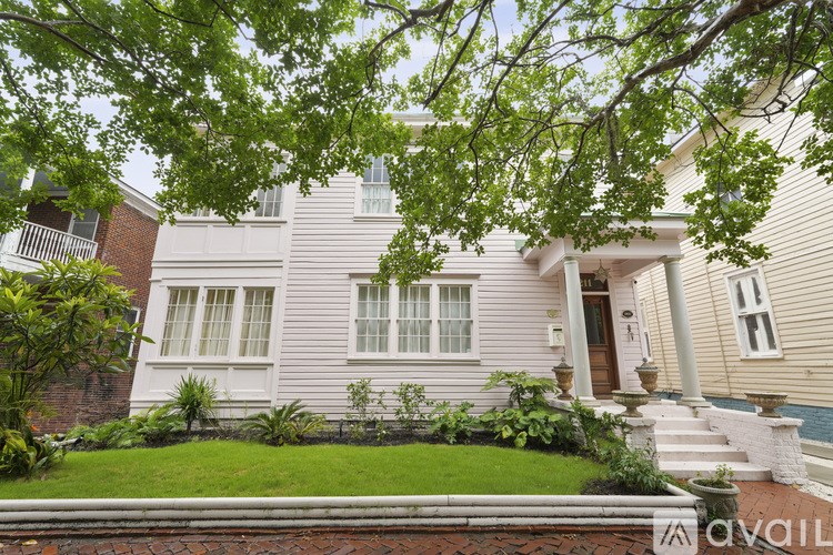 A house with a front yard and a tree branch in the foreground.