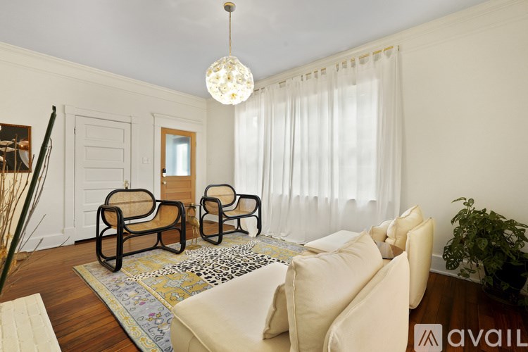 A living room with a white couch, a chair, and a rug.