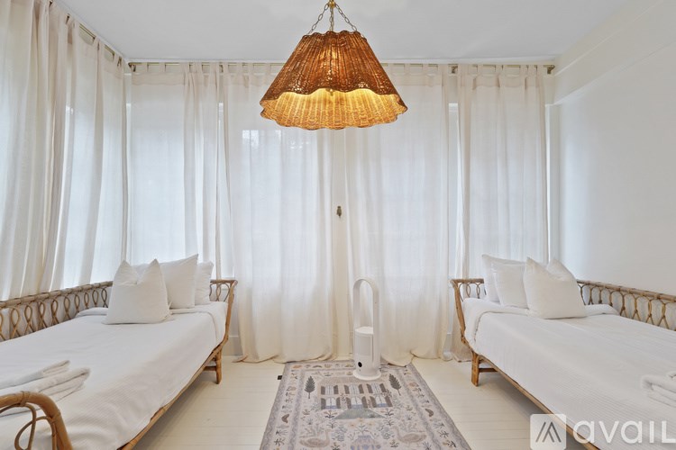 A bedroom with two beds, a hanging light, and a rug on the floor.