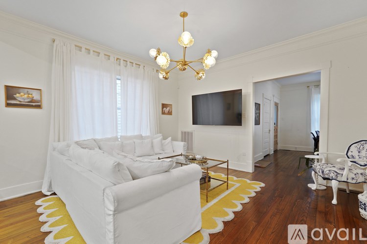 A living room with a white couch and a chandelier.
