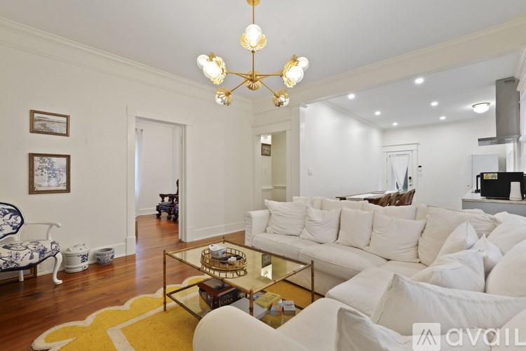 A living room with a white couch and a yellow rug.