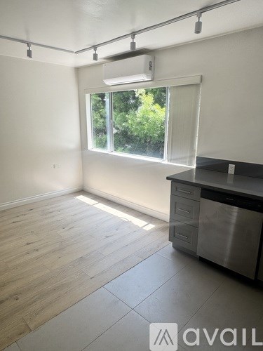 A kitchen with a stainless steel dishwasher and wooden flooring.