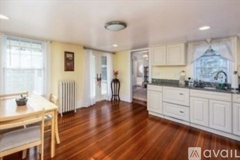 A kitchen with white cabinets and a wooden floor.