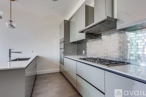 A modern kitchen with a stove top oven and a tiled backsplash.