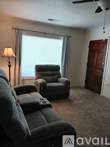 A living room with a grey couch and a fan.