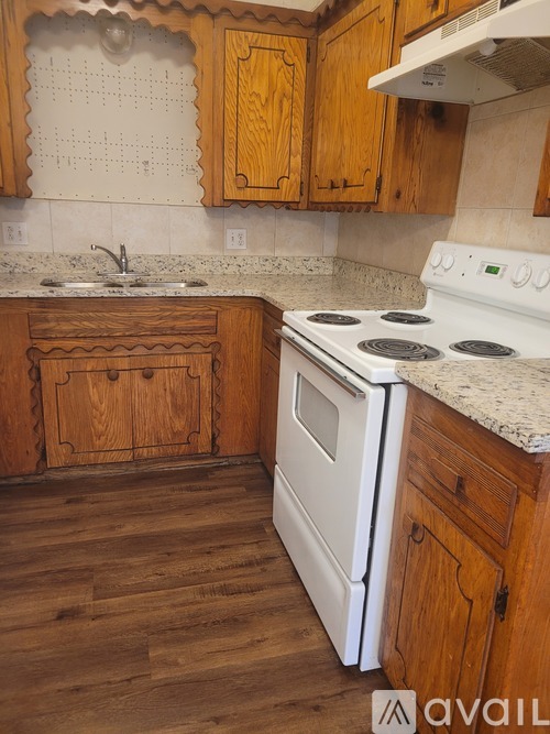 A kitchen with wooden cabinets and a white stove top oven.