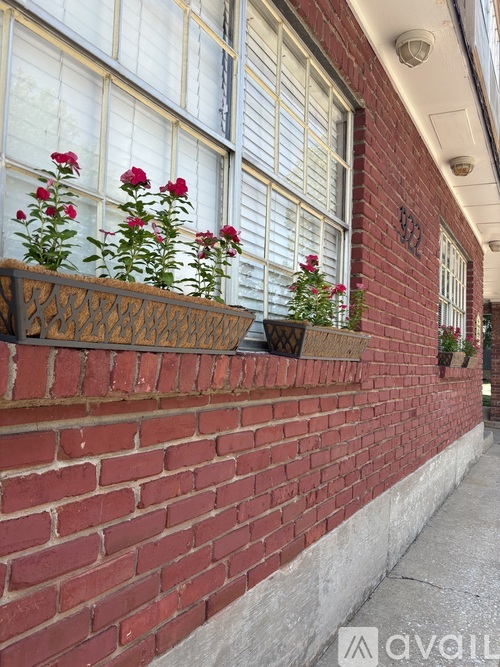 A red brick wall with a window and flowers.