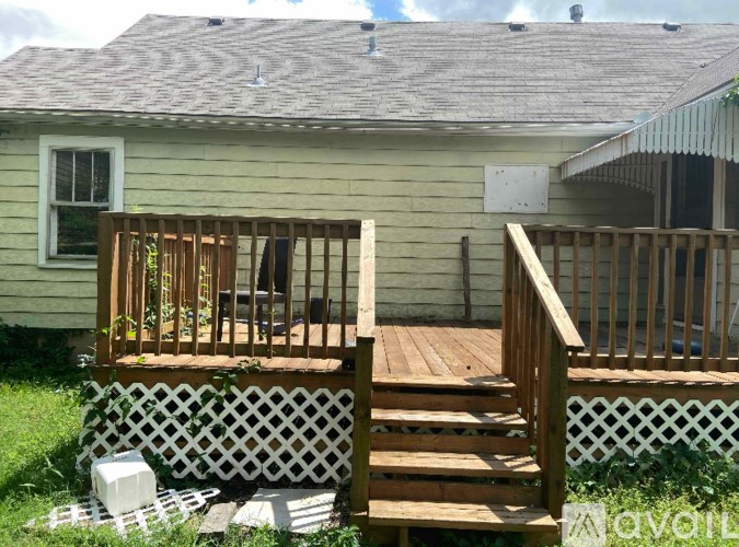 A wooden deck with a lattice fence is in front of a house.