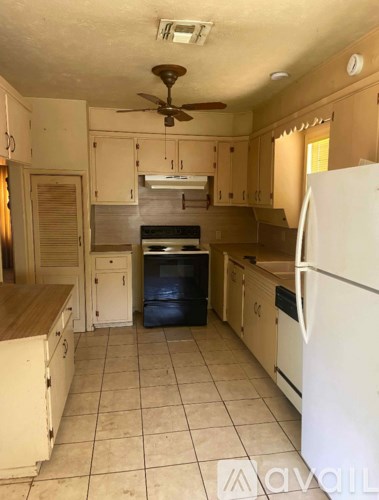 A kitchen with a white fridge and a fan on the ceiling.