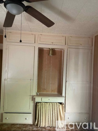 A room with a ceiling fan and a cabinet with a drawer.