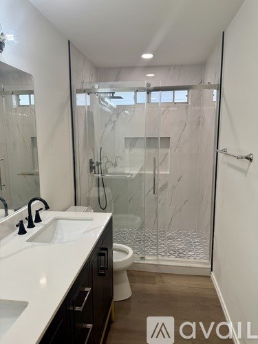 A bathroom with a walk-in shower and a double sink vanity.