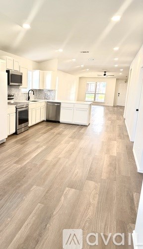A spacious kitchen with wooden flooring and white walls.