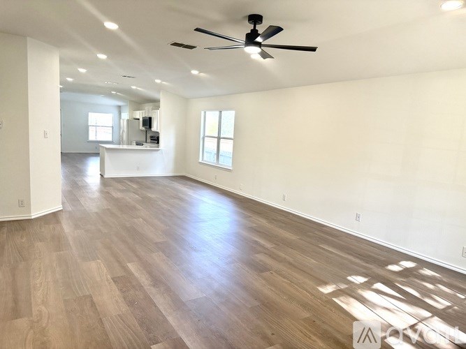 A spacious room with wooden flooring and a ceiling fan.