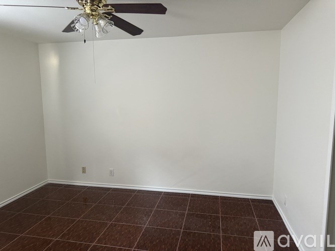 A room with a ceiling fan and brown tiled flooring.