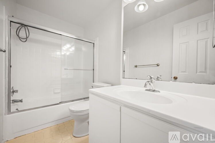 A white bathroom with a toilet, sink, and shower.