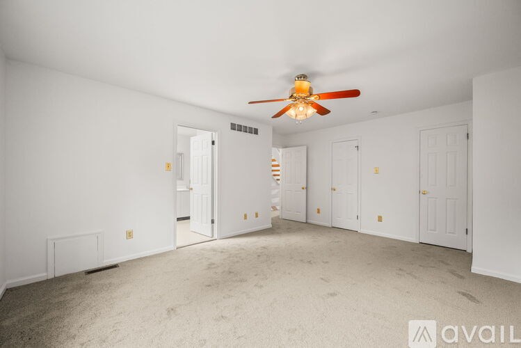 A room with a ceiling fan and carpeted floor.