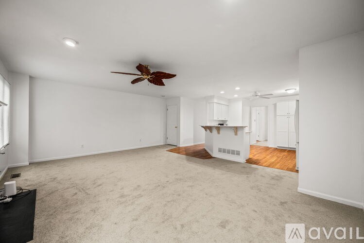 A spacious room with a ceiling fan and a carpeted floor.