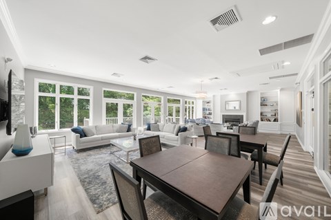 A modern living room with a wooden dining table and chairs, a white sofa, and a television.
