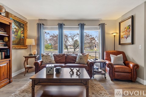 A living room with brown leather furniture and a large window.