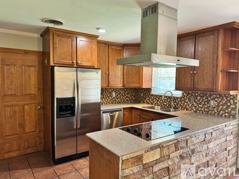 A kitchen with wooden cabinets and a stainless steel refrigerator.