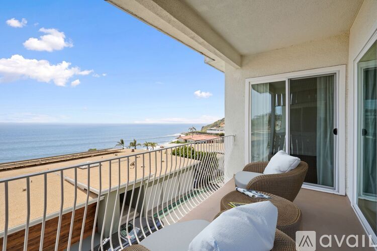 A balcony with a view of the ocean and palm trees.