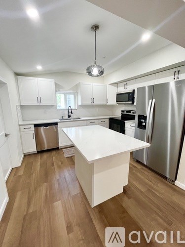 A kitchen with white cabinets and a wooden floor.