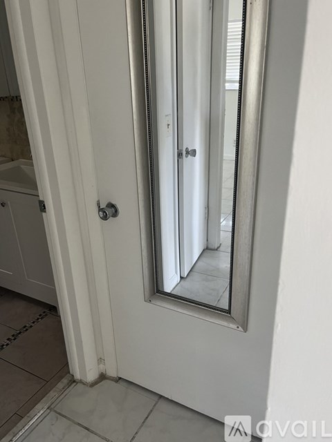 A white door with a mirror on the right side.