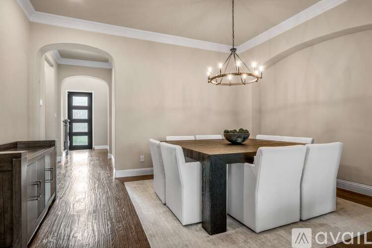 A dining room with a wooden table and white chairs.