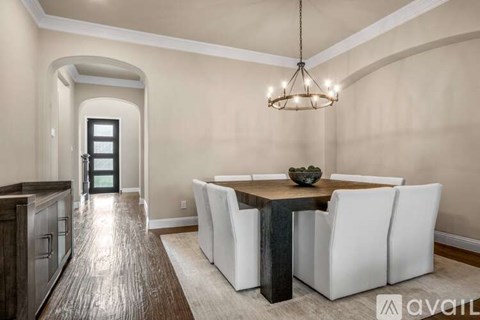 A dining room with a wooden table and white chairs.