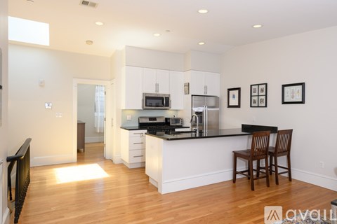 A kitchen with white cabinets and a wooden floor.