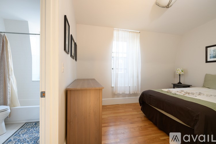 A bedroom with a bed, nightstand, and a wooden cabinet.