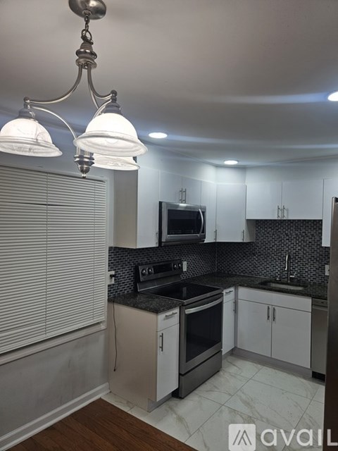 A kitchen with a black countertop and white cabinets.